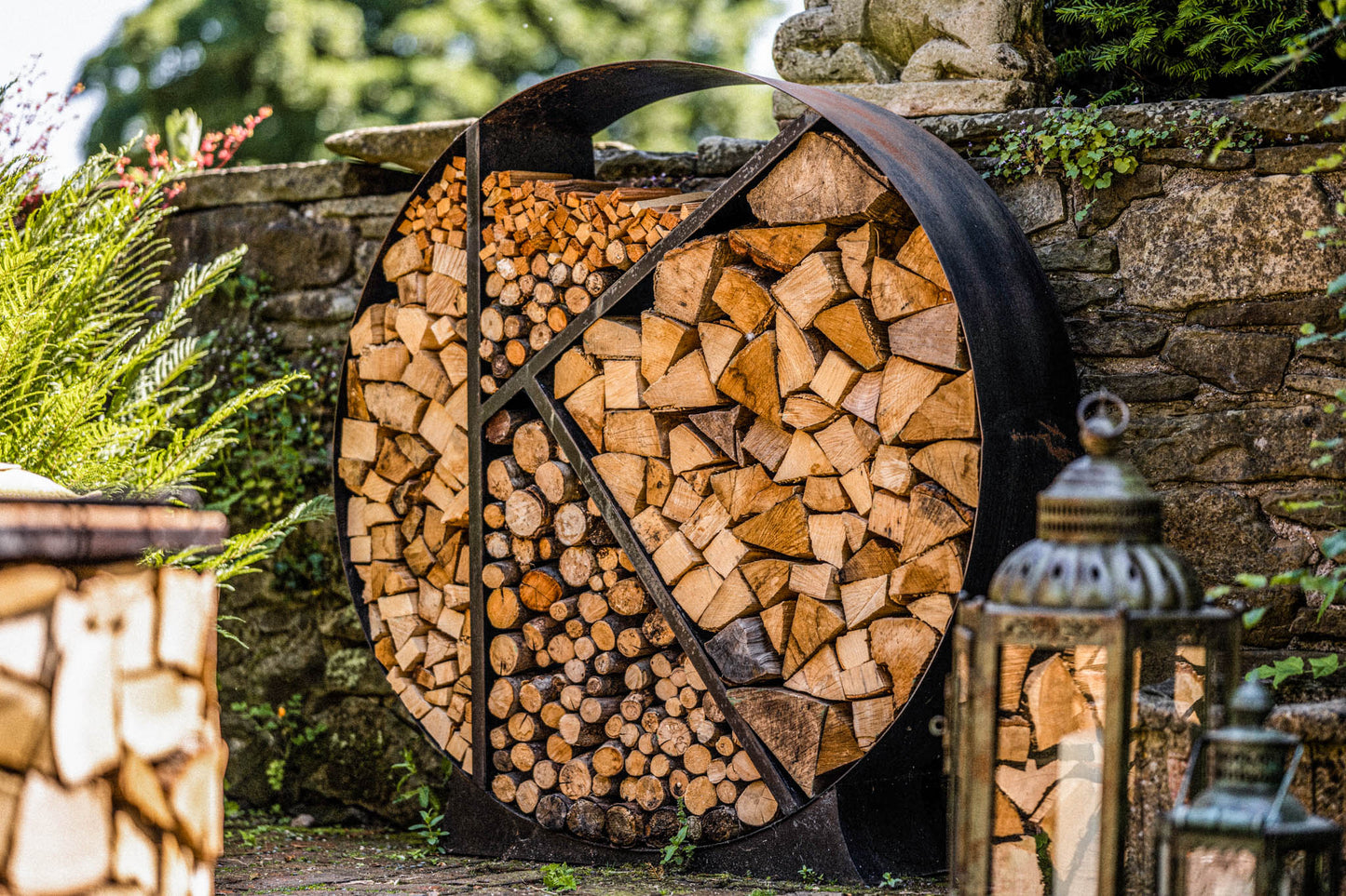 Stylish round metal firewood rack organizing split logs in a rustic patio setting