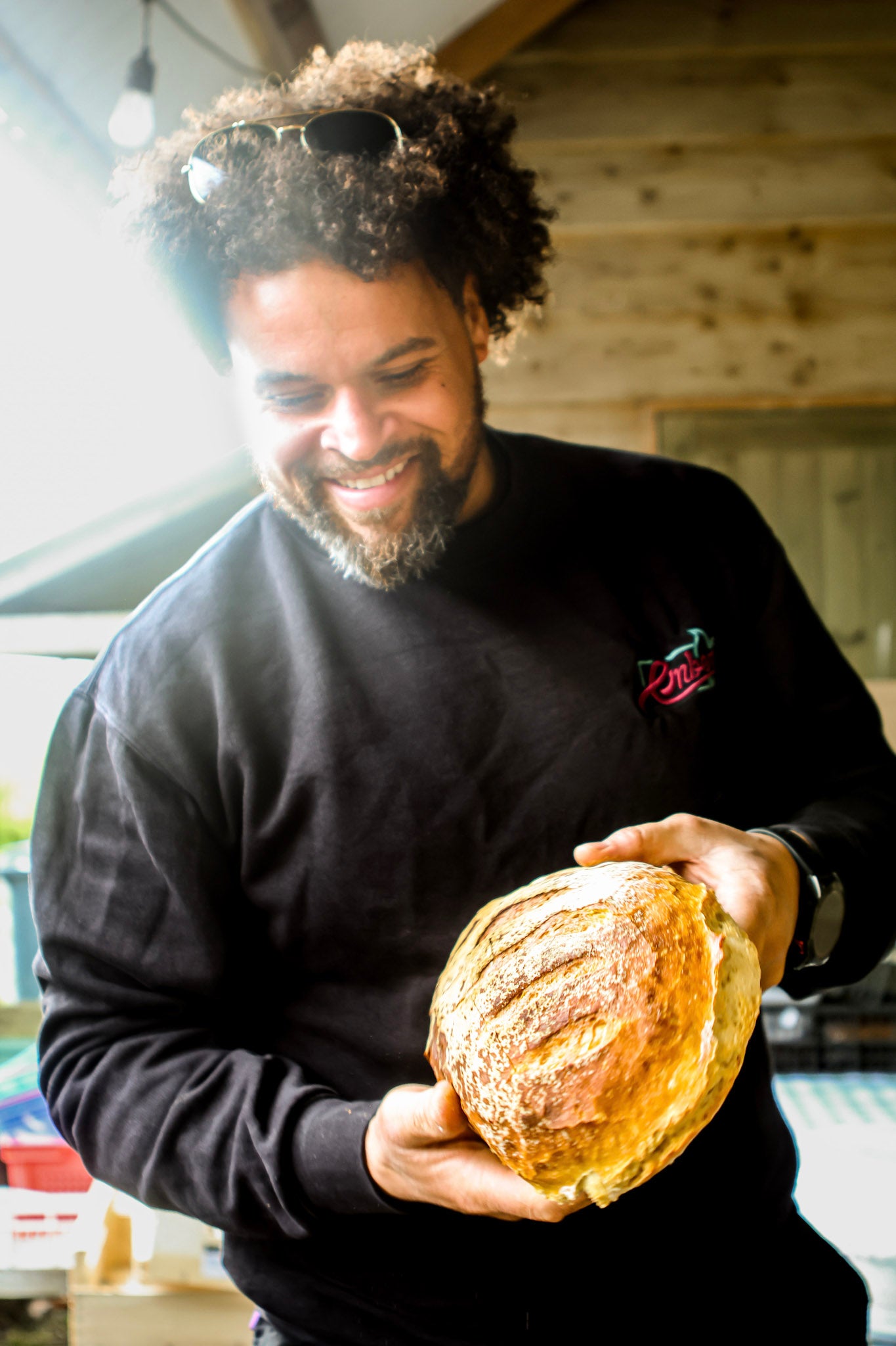 Man holding a loaf of bread in a rustic setting