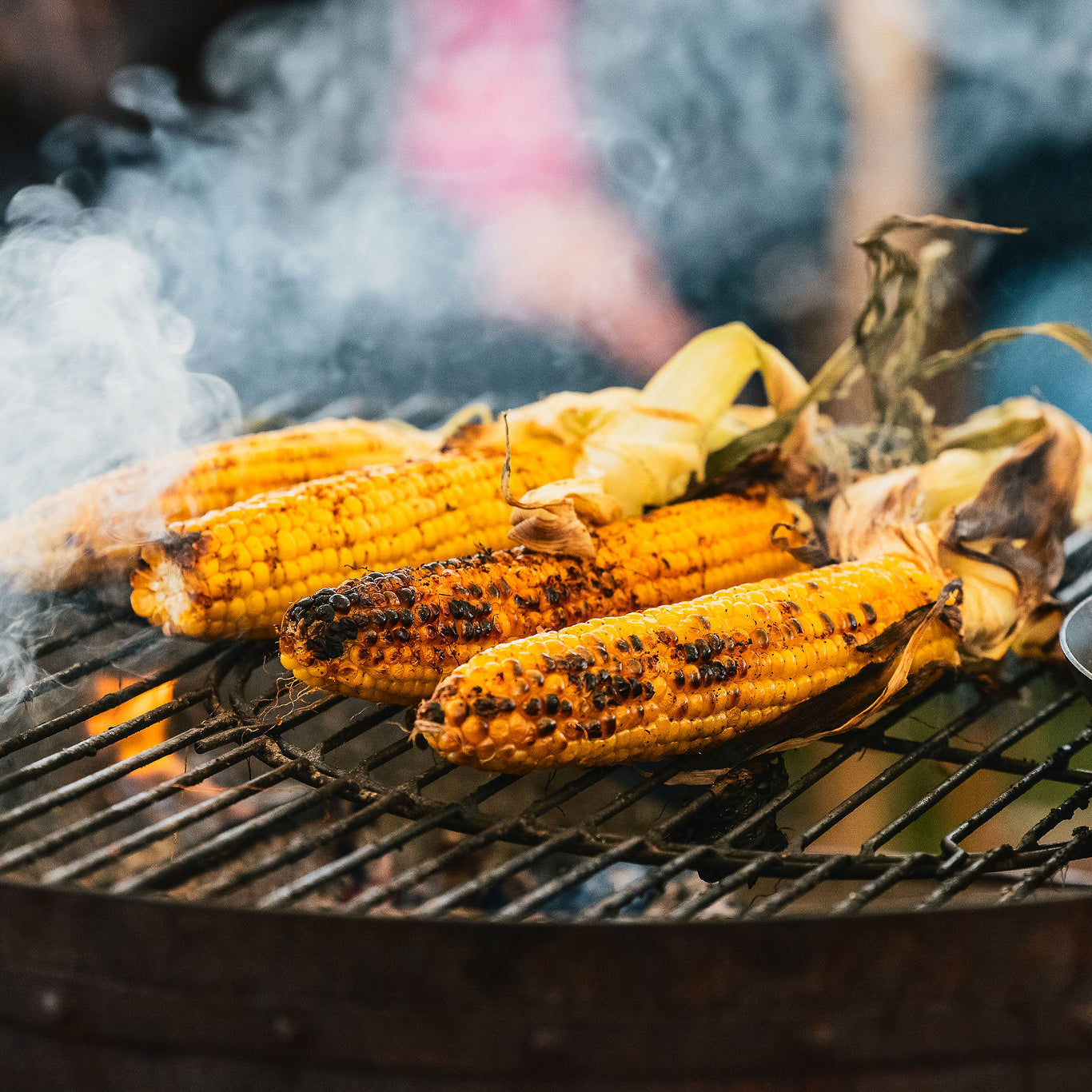 Grilled corn on a BBQ with smoke rising