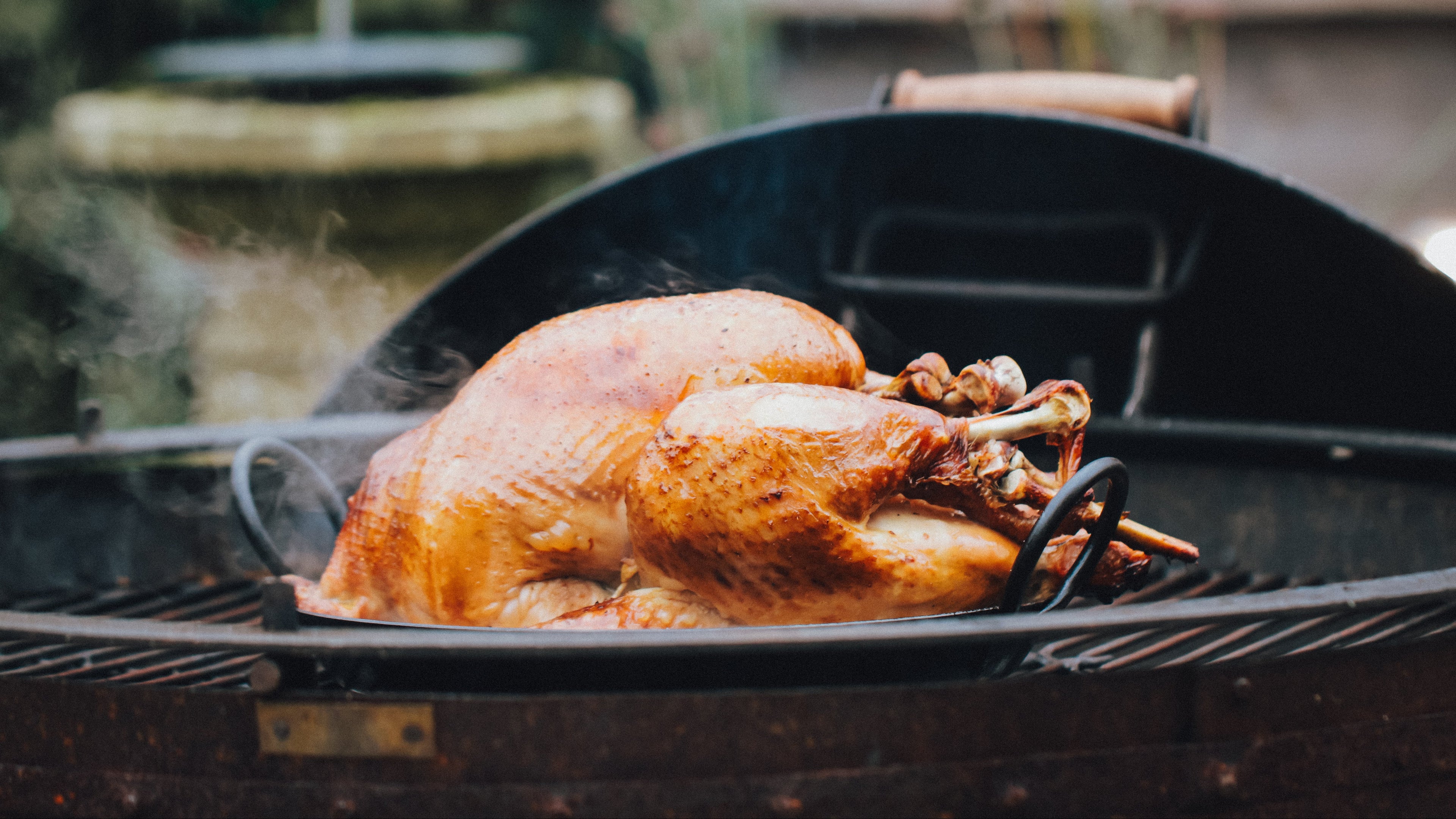 turkey cooking on a BBQ Grill with a christmas tree in a blurred background