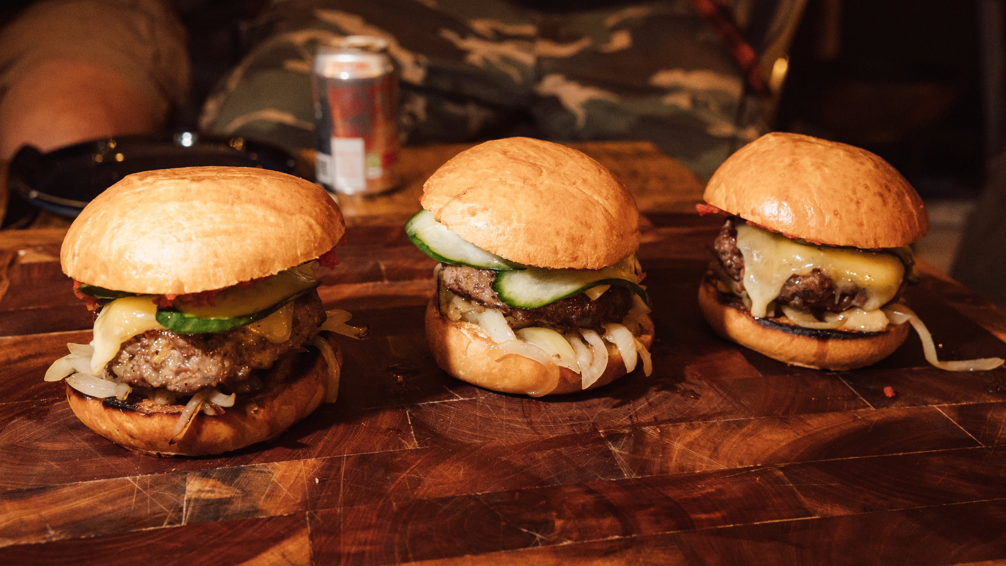 Three burgers on a wooden surface with a blurred background