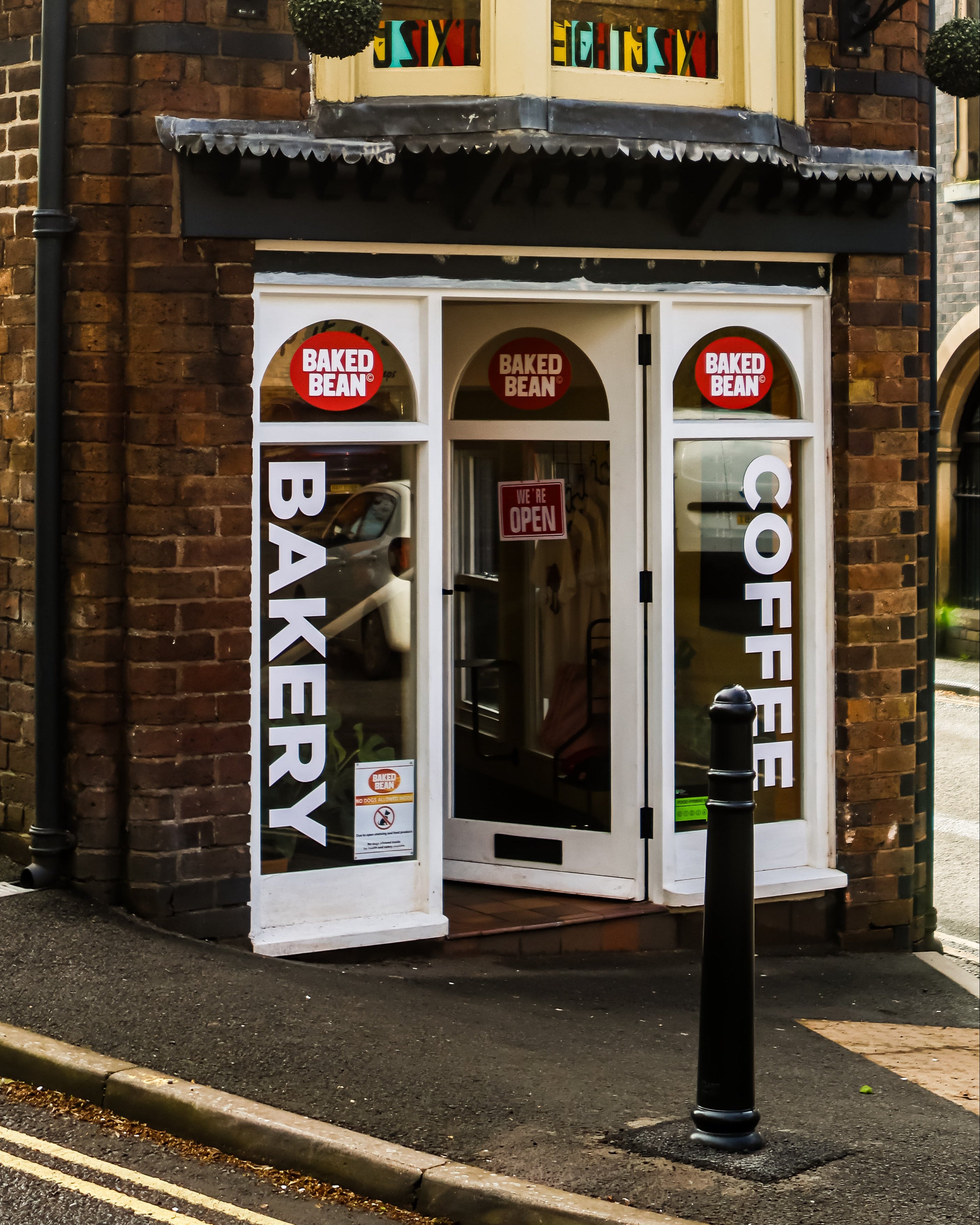 Baked Bean Bakery and coffee shop entrance with signs on a brick building