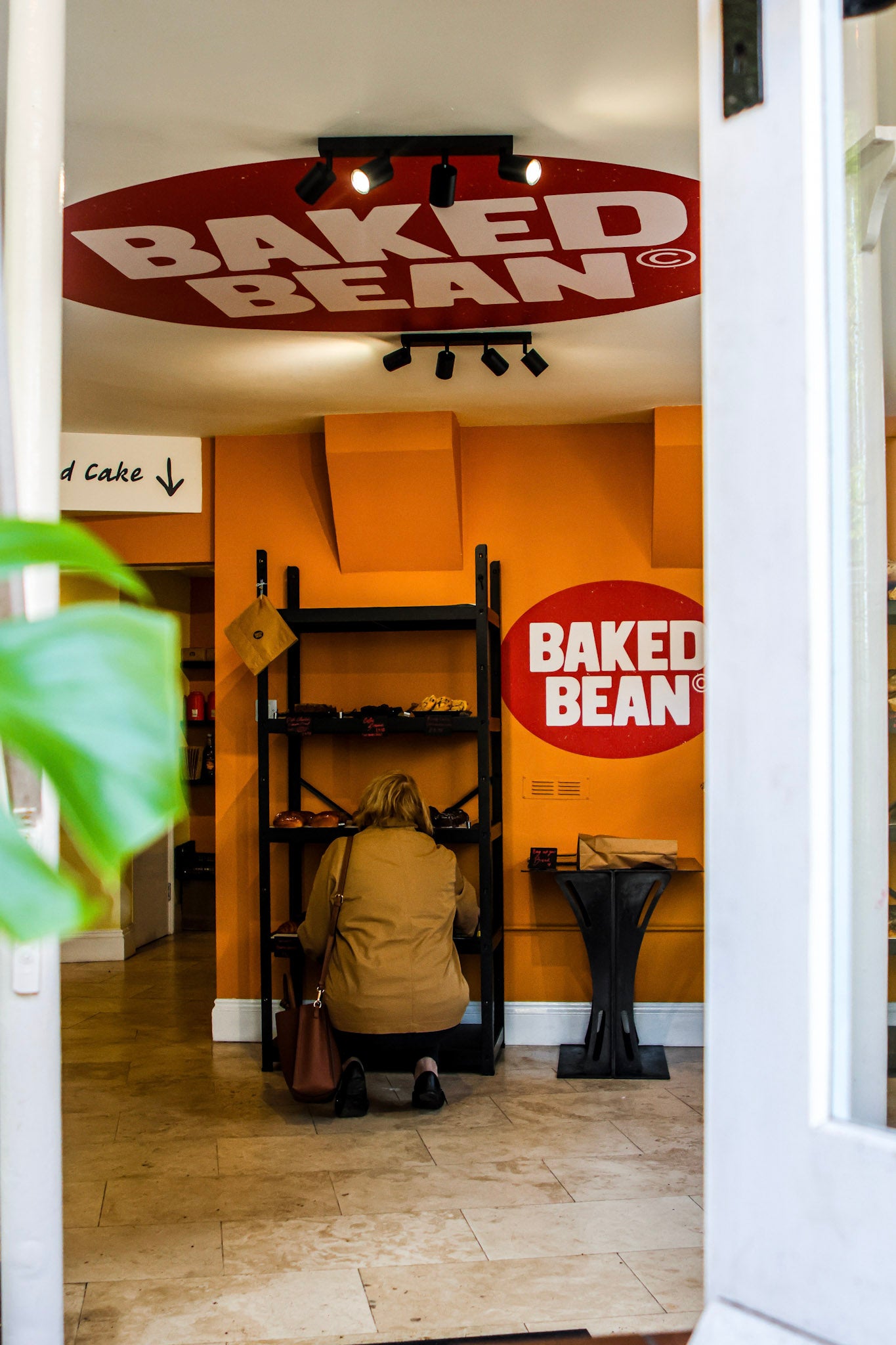 Person sitting inside a store with 'Baked Bean' branding on the walls.