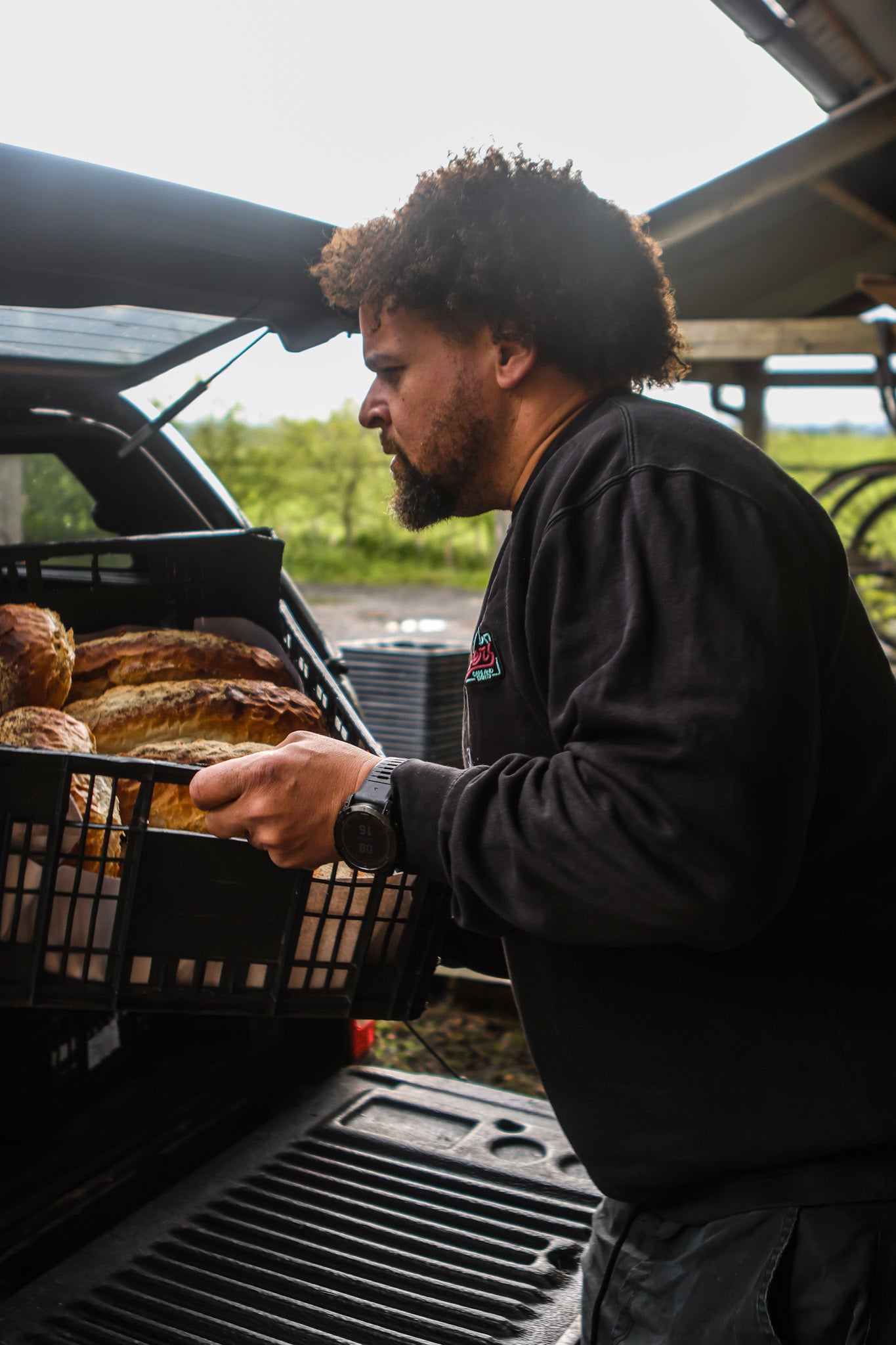 Man unloading bread from a car trunk into a basket