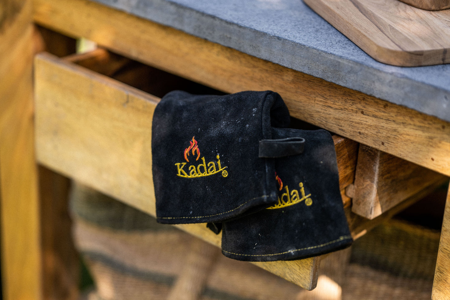 Black gloves with 'Kadai' logo on a wooden surface