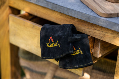 Black gloves with 'Kadai' logo on a wooden surface
