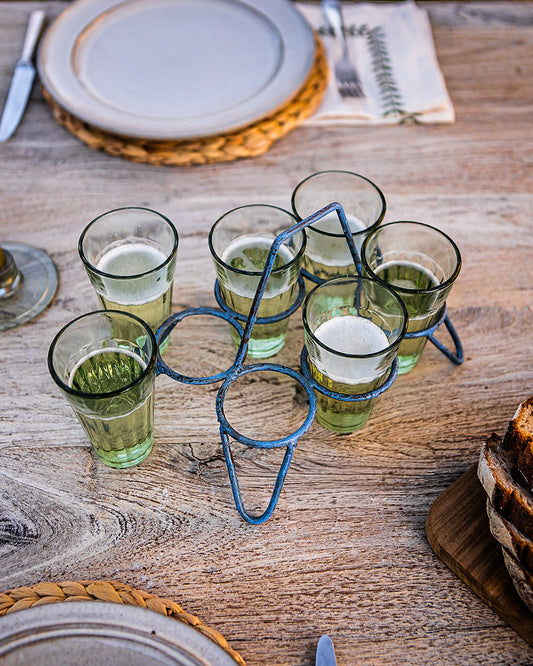 Blue Kadai set of chai glasses in metal holder on rustic outdoor table with place setting