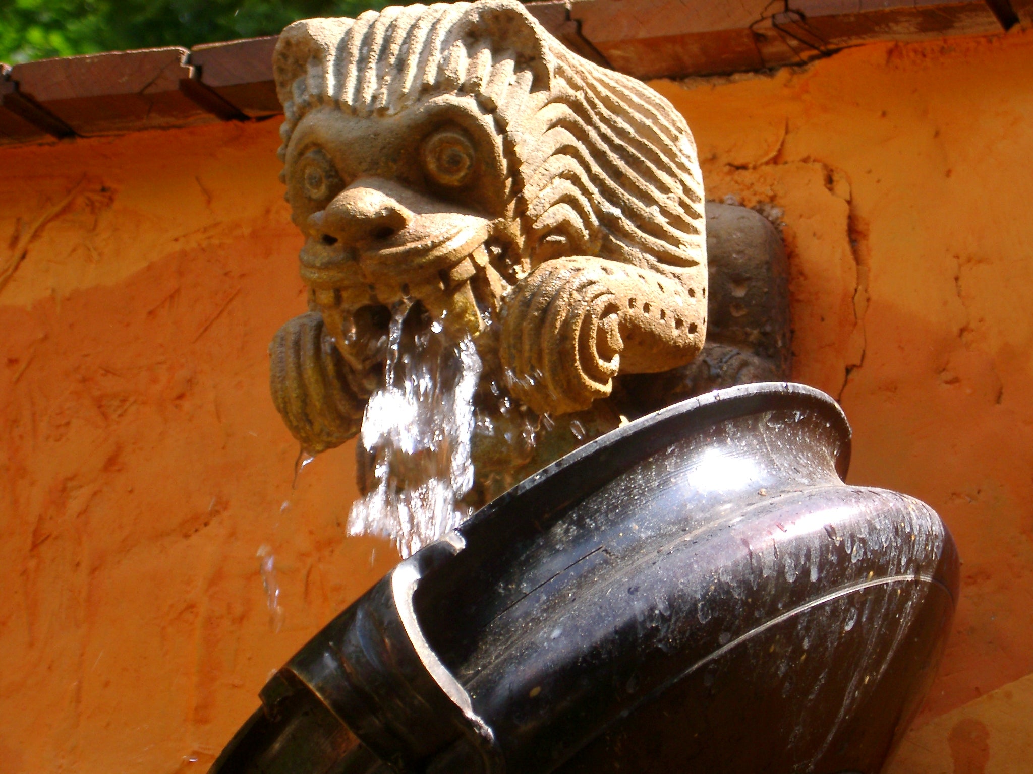 Chelsea flower show Fountain with lion head spout against an orange wall