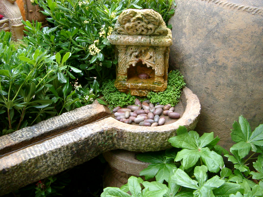 Decorative water spout with small pebbles inside in a garden setting