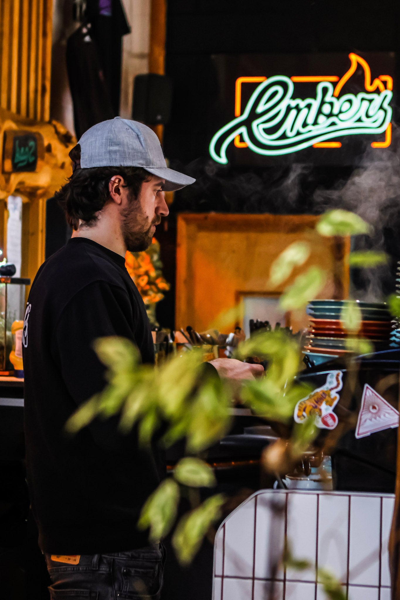 Man working behind a counter with a neon sign in the background