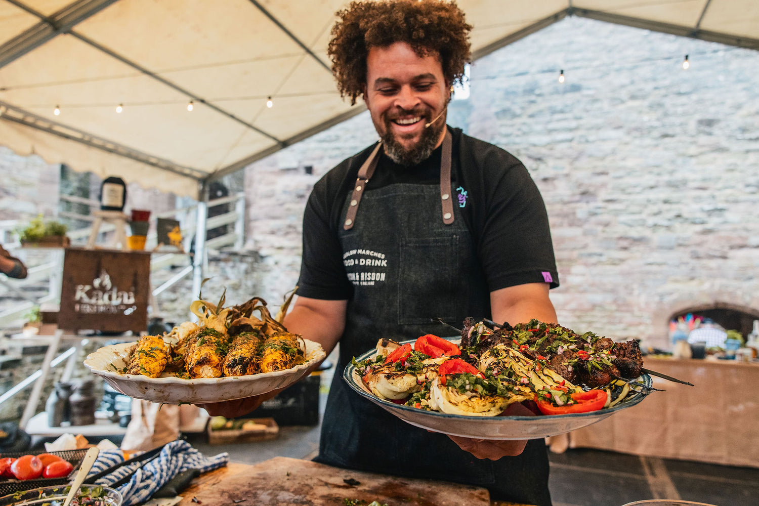 Adam Purnell chef holding two plates of food on the fire stage at Ludlow Food Festival