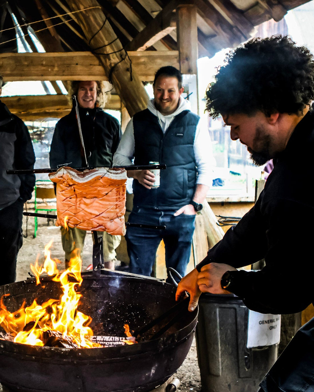 Group of people around two large kadai fire pits in an outdoor setting.