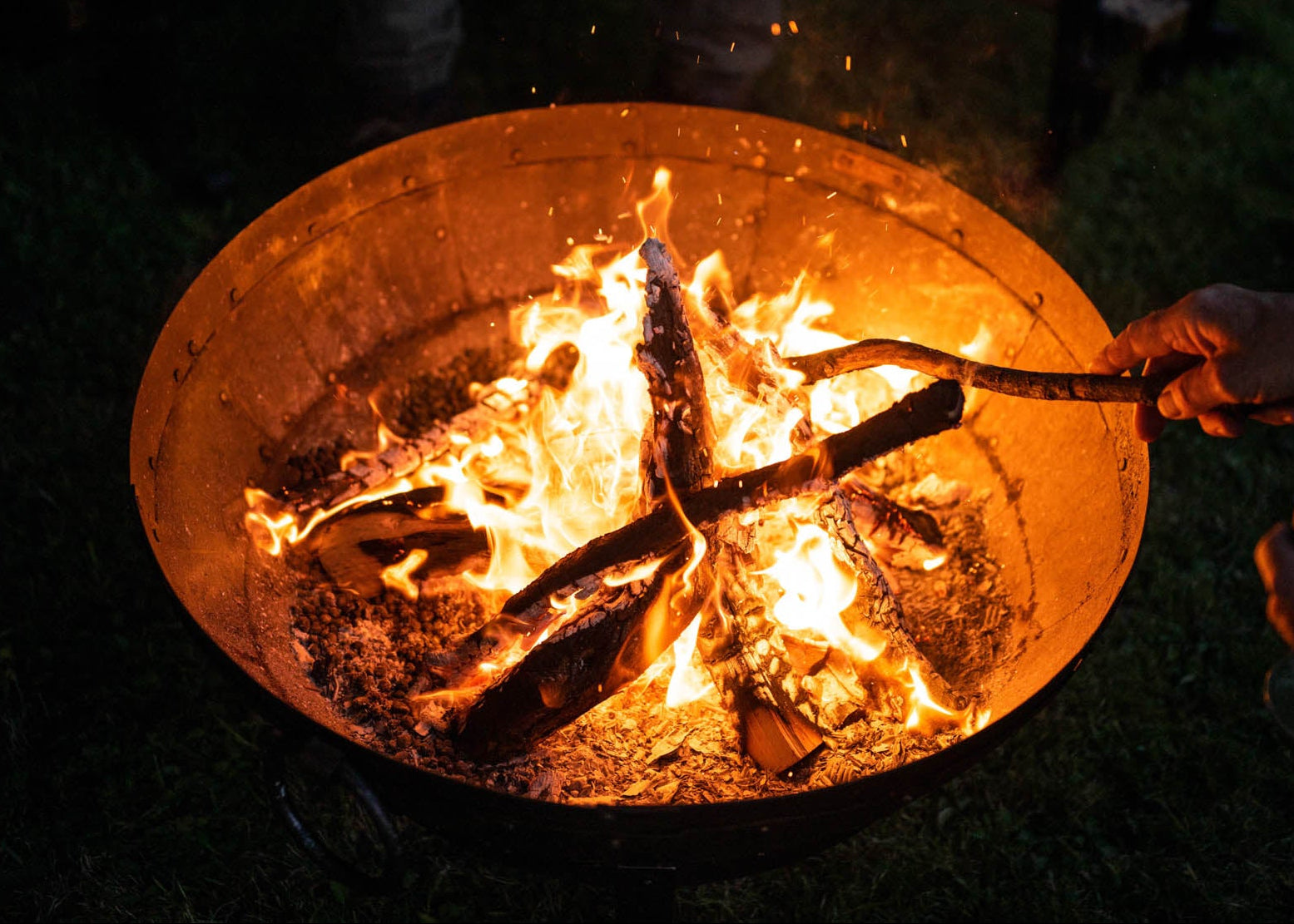 Kadai Fire Pit at night with a stack of logs in the fire.
