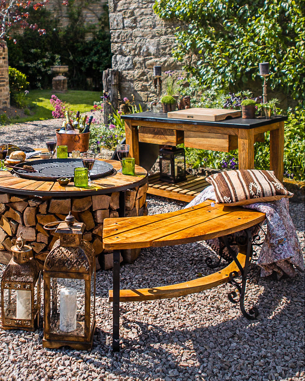 Curved wooden outdoor bench beside a rustic fire pit dining area in a garden patio