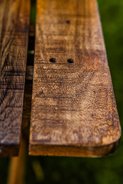 Close-up detail of a rustic wooden café table showcasing rich natural grain, weathered texture, and handcrafted slatted construction