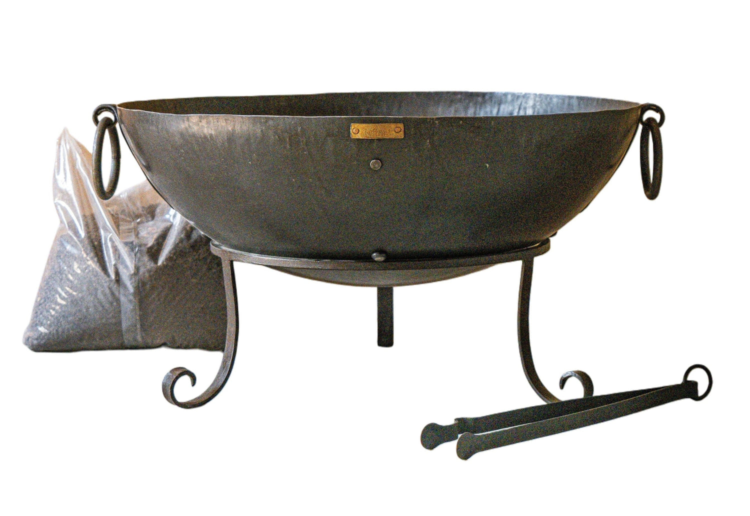 A metal bowl-shaped fire pit with a stand, shown on a plain white background with a pair of tongs.