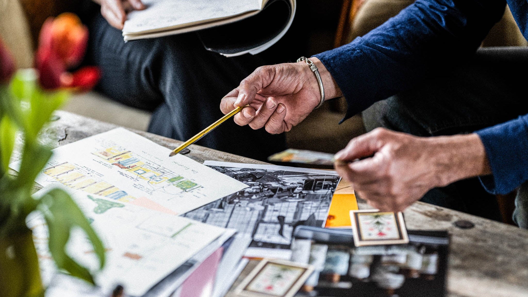 Person drawing on a piece of paper with a pencil, surrounded by stationery items.
