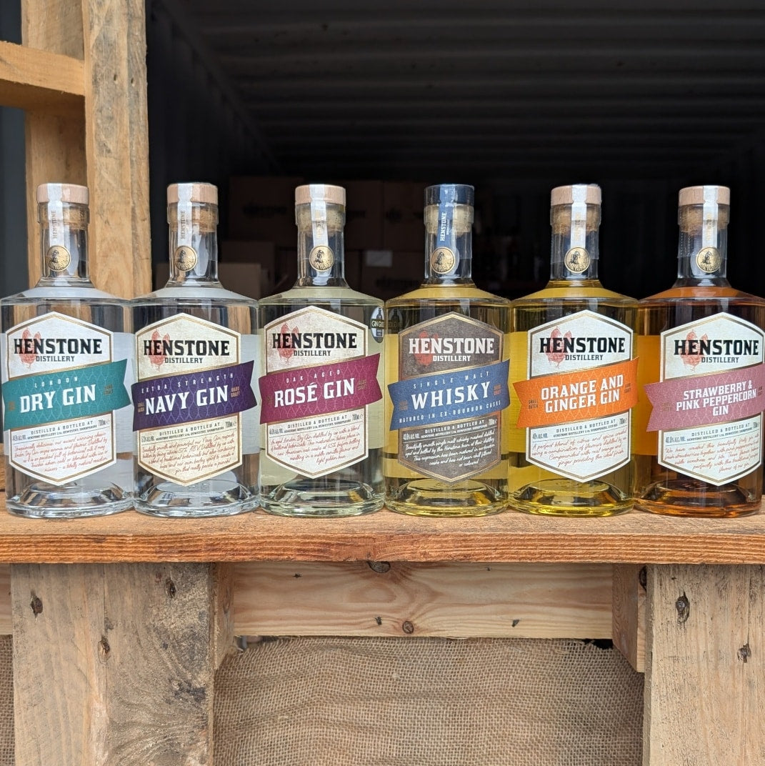 Collection of Henstone gin bottles on a wooden shelf with a rustic background.