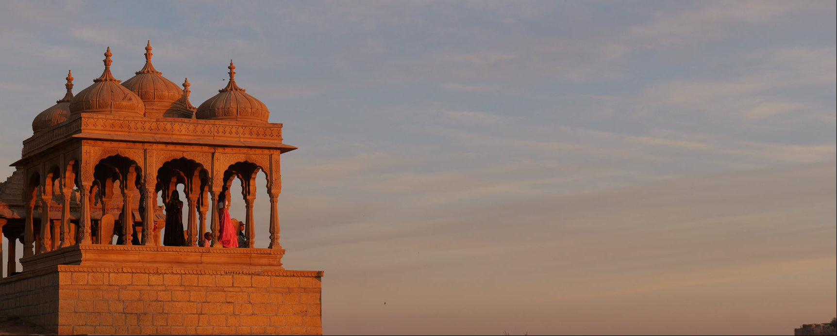 Traditional architectural structure with temple domes against a sunset sky