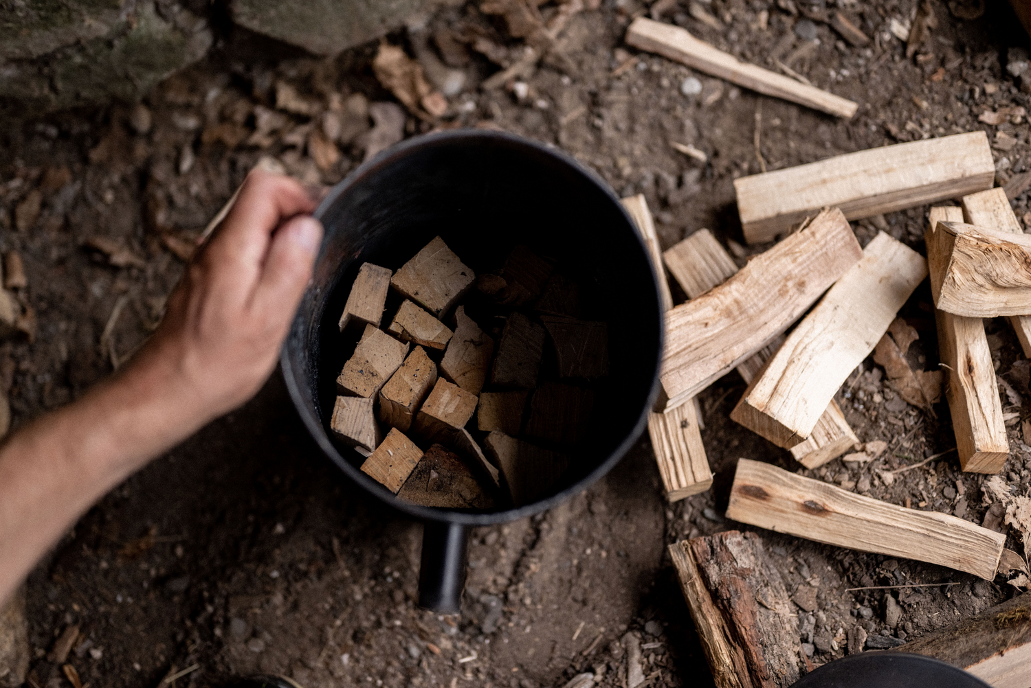 Someone filling up a homemade charcoal maker with peices of wood
