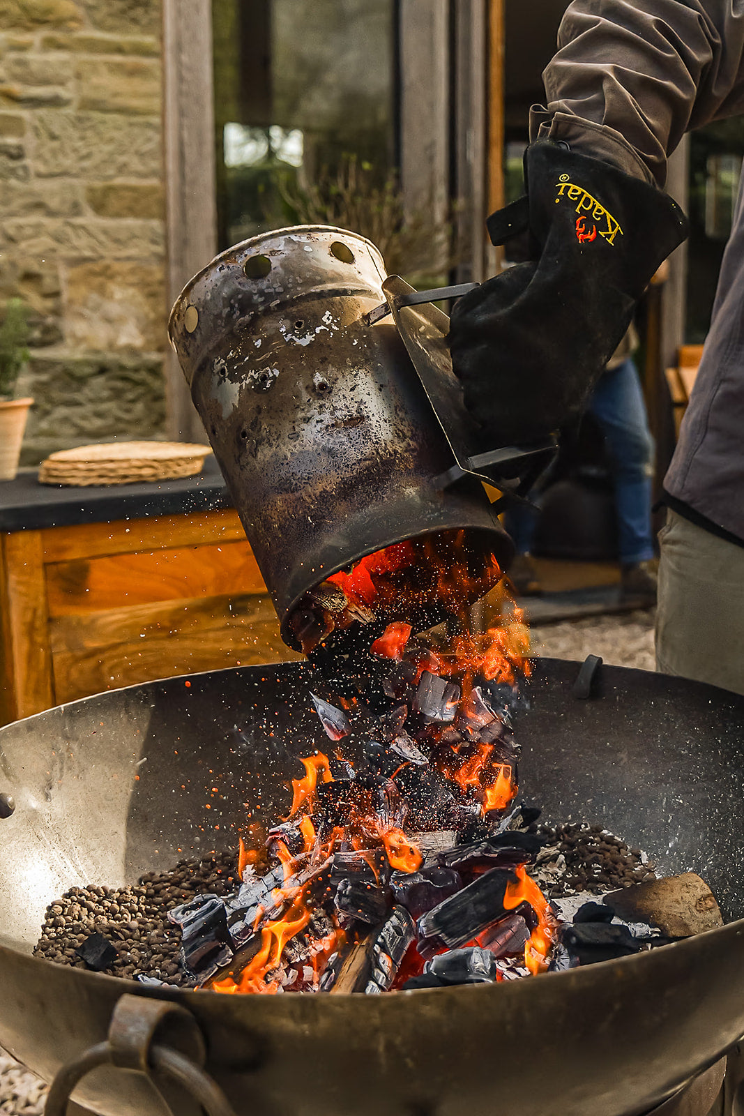 Person pouring hot coals from a charcoal starter into a bbq.