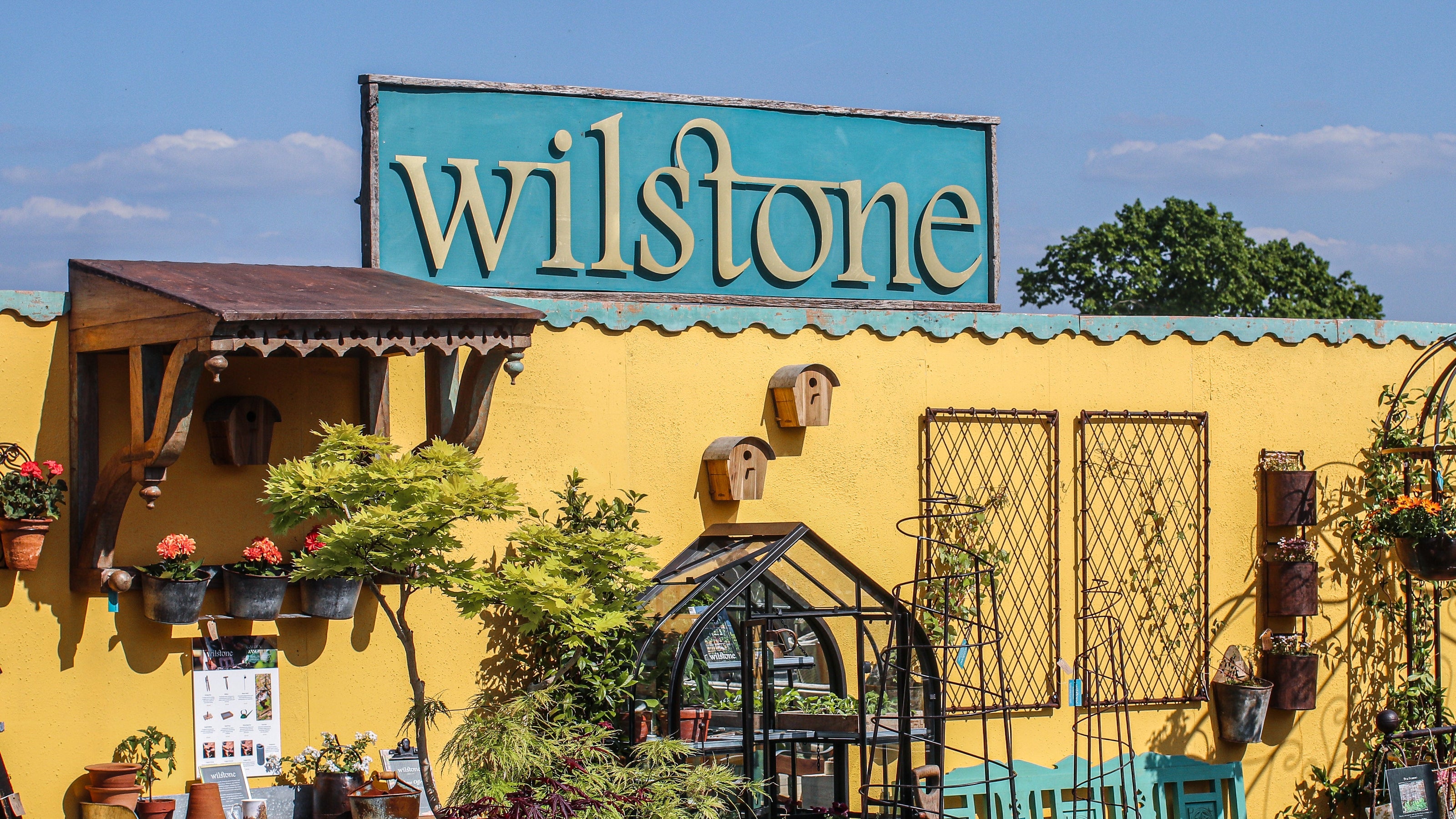 Yellow building with 'wilstone' sign, outdoor decor, and plants.
