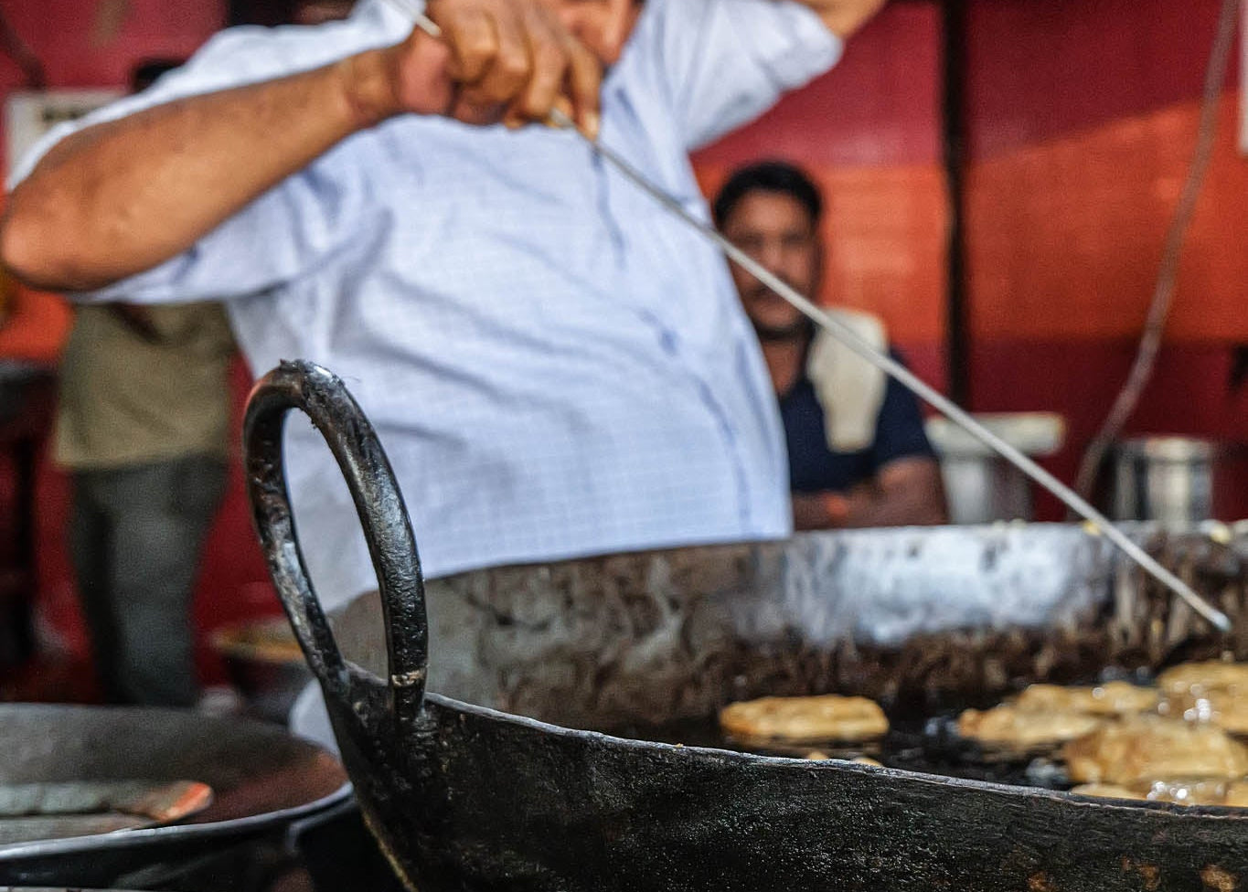 Man cooking food in a large wok at a restaurant.