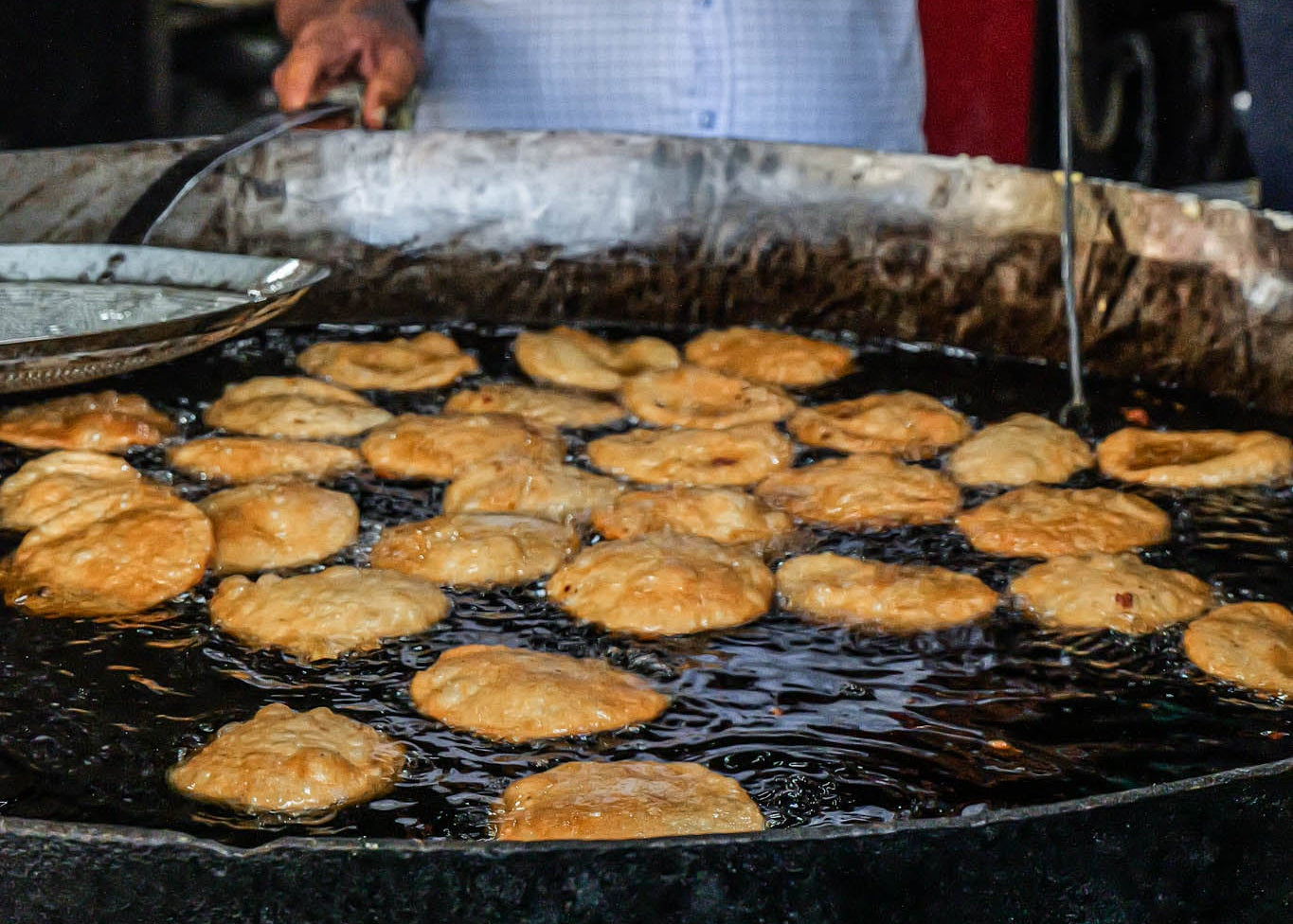 Man cooking food on a large griddle in india