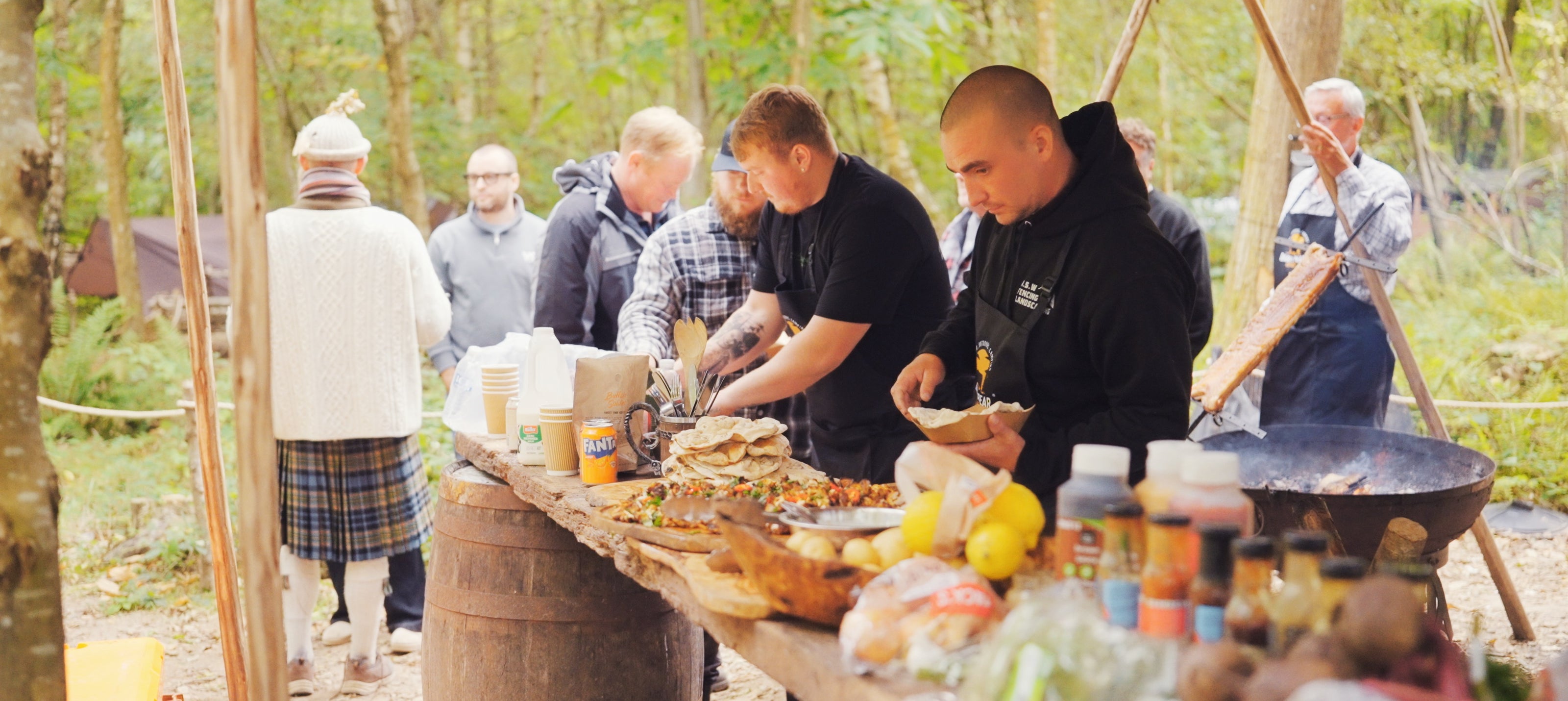 People preparing food outdoors in a forest setting