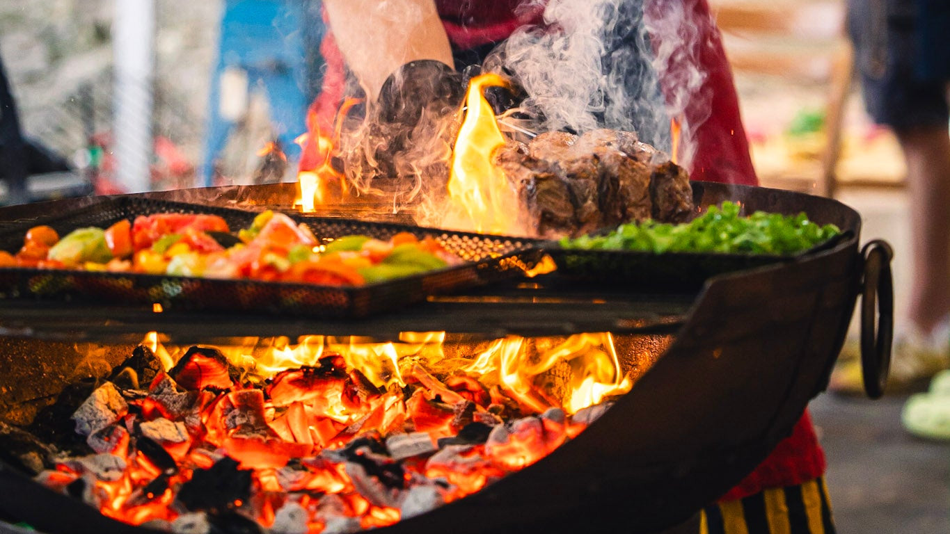 Person cooking on a recycled kadai firebowl with flames and vegetables