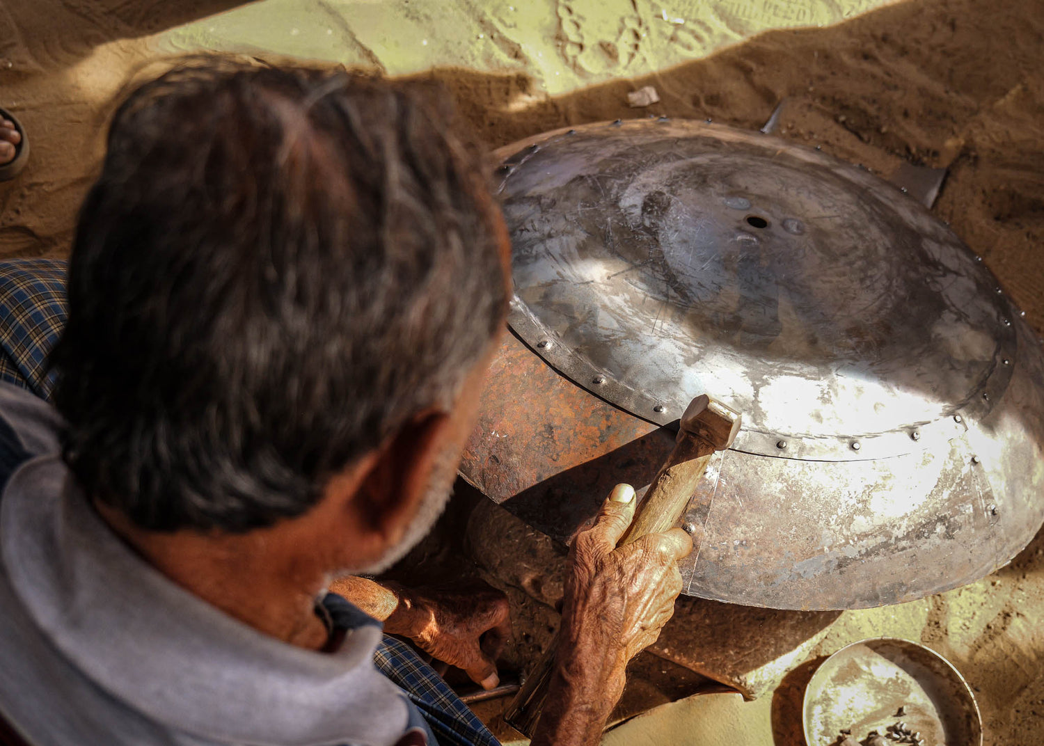 person making a kadai recycled firebowl in india