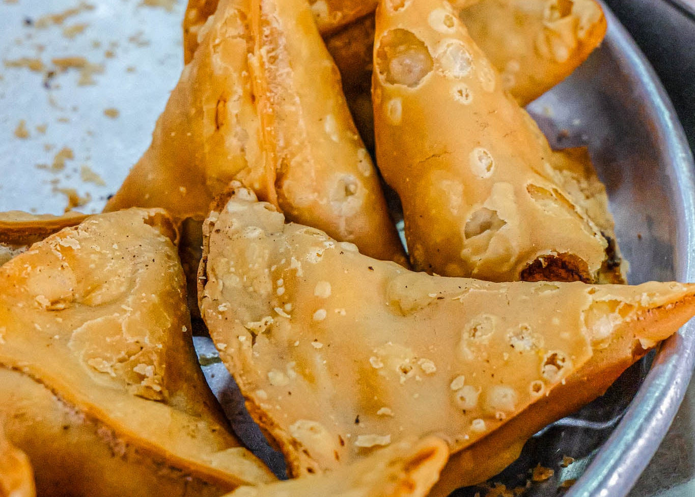 Baked samosas on a metal tray with a blurred background