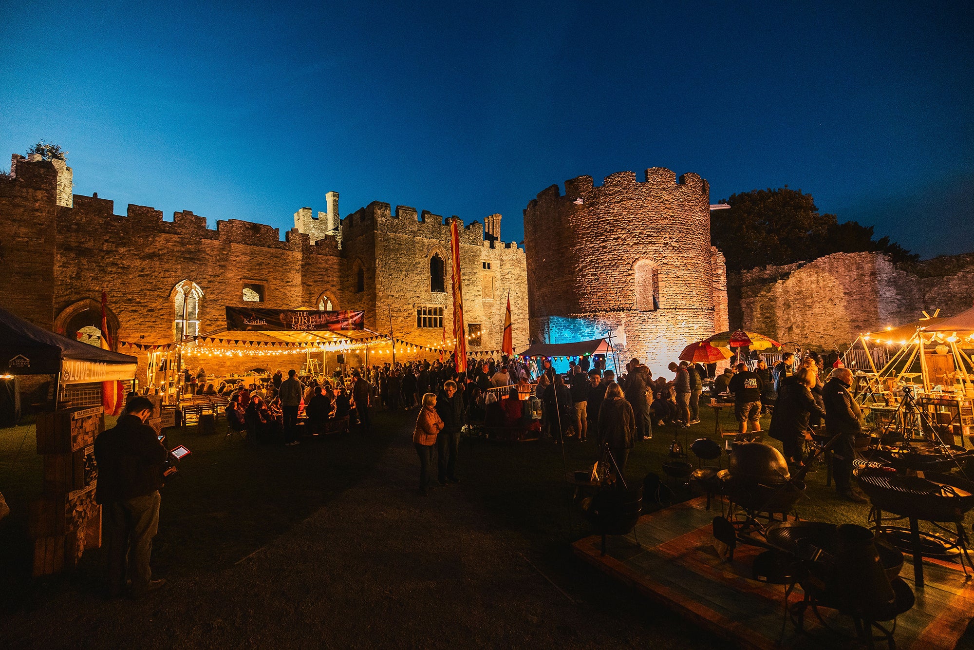 Castle with market stalls and people at night at Ludlow Food Festival