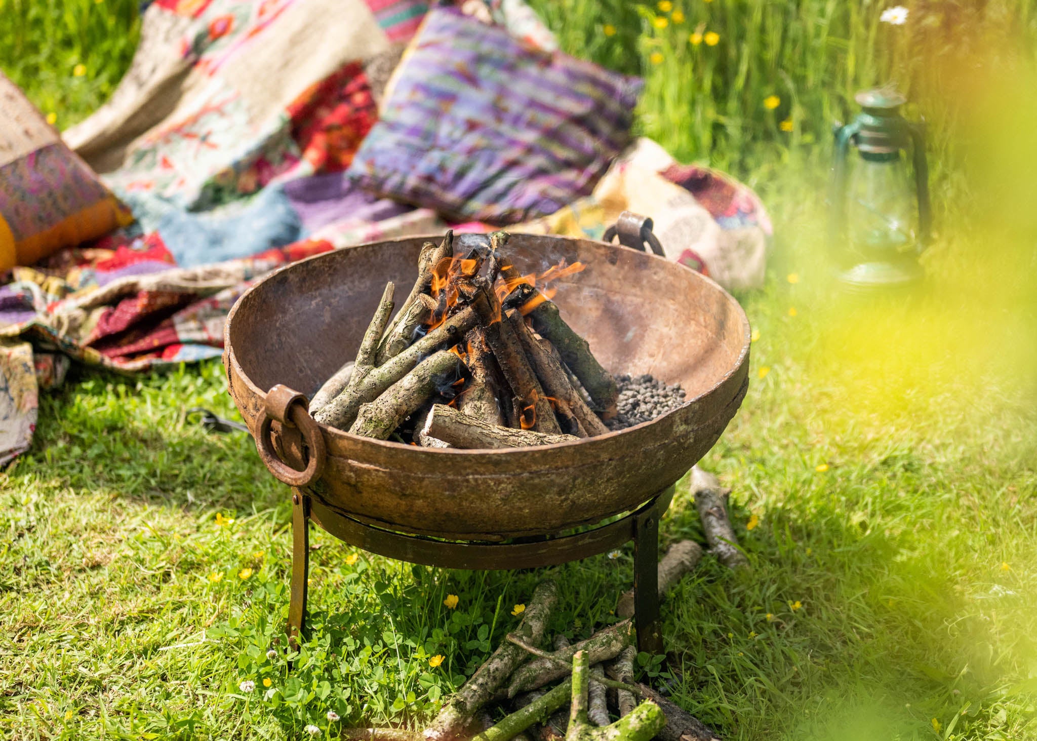 kadai Fire pit with burning logs on a grassy outdoor setting