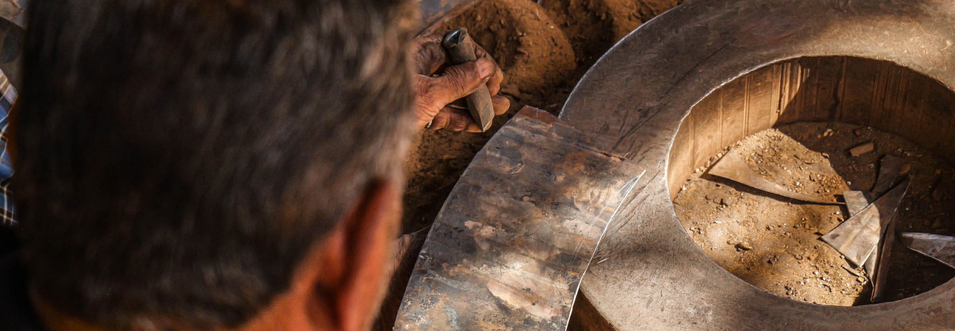 Person working with a large metal wheel or gear in an industrial setting