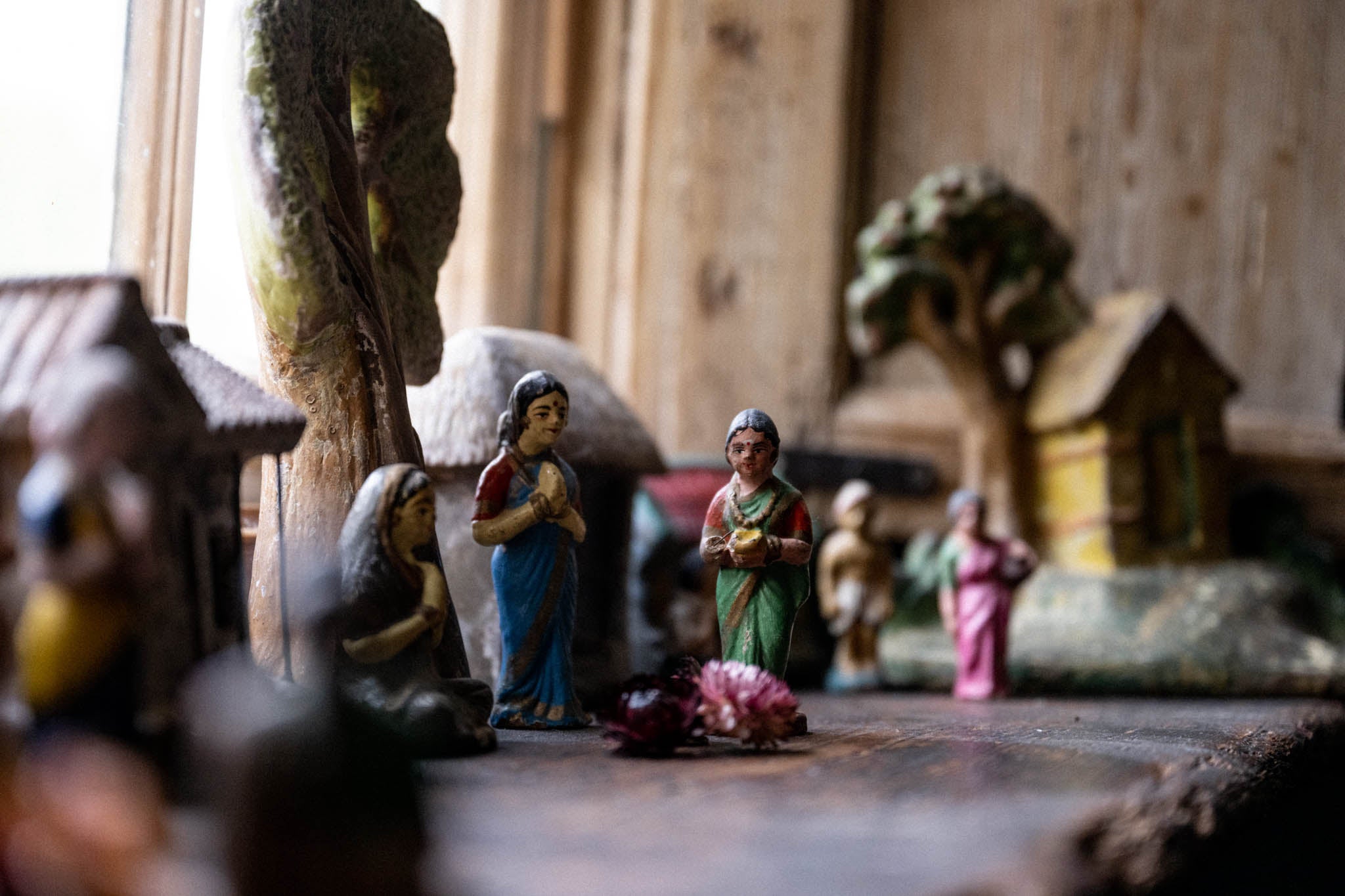Small figurines of a nativity scene on a wooden surface with blurred background
