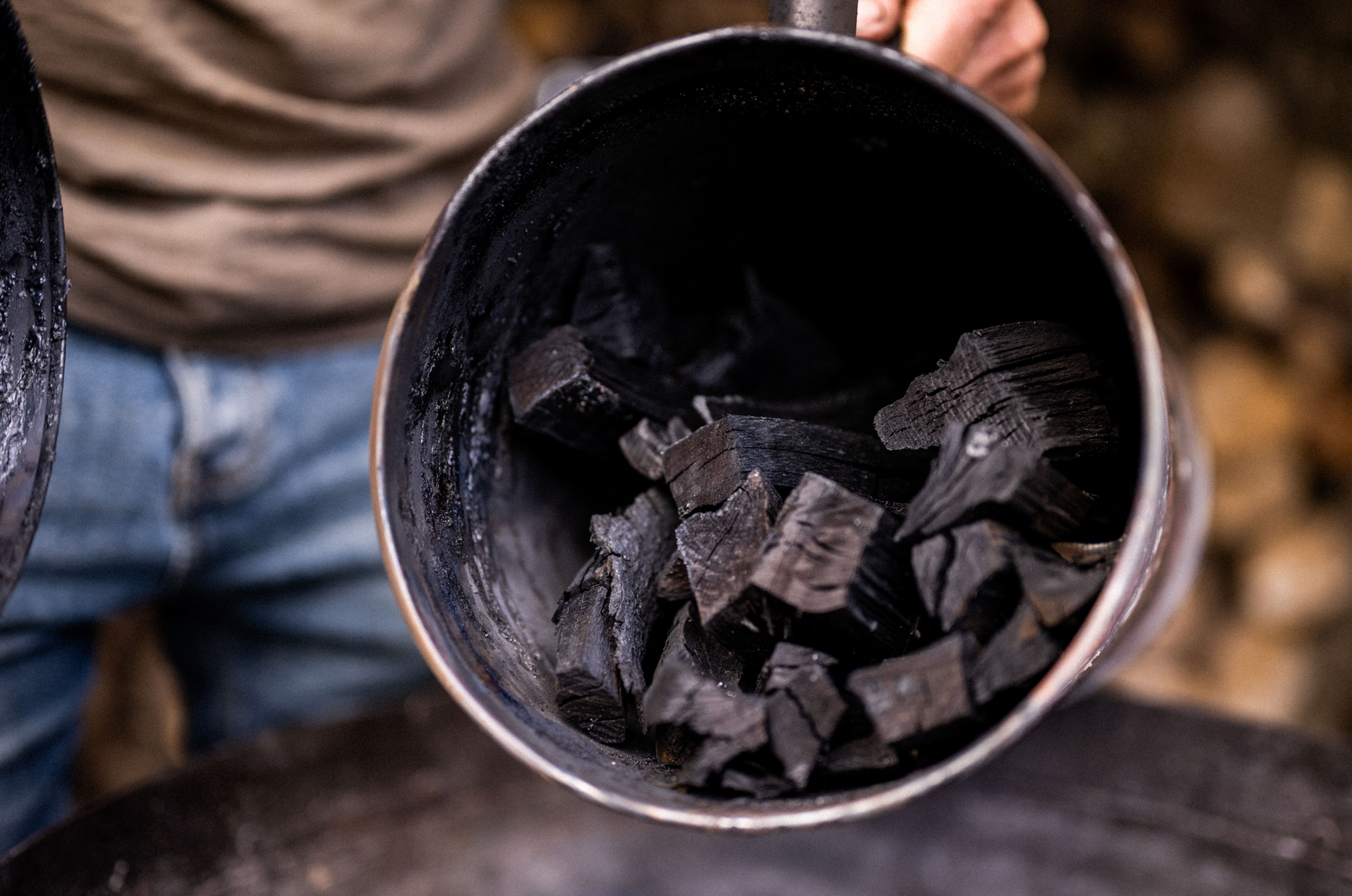 Someone holding a charcoal maker open with homemade charcoal inside