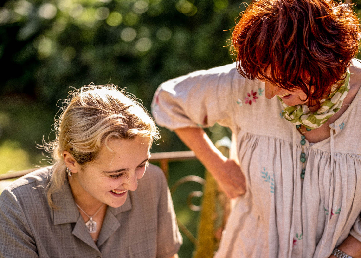 Two women sitting outdoors with a blurred natural background