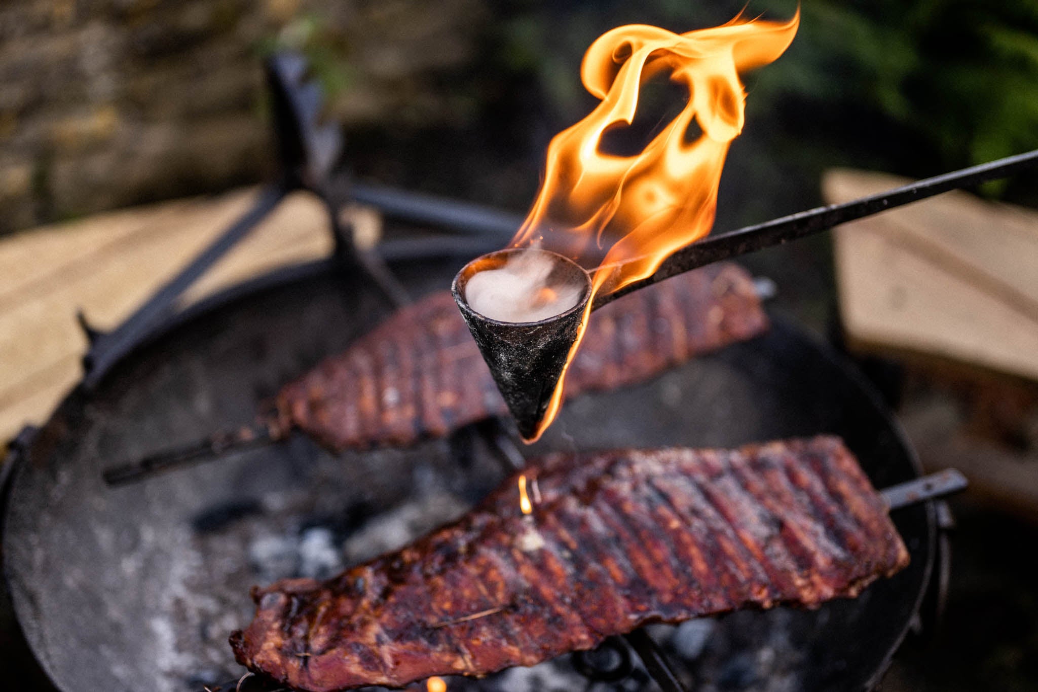 Flambadou fire tools being used to cook meat on a grill
