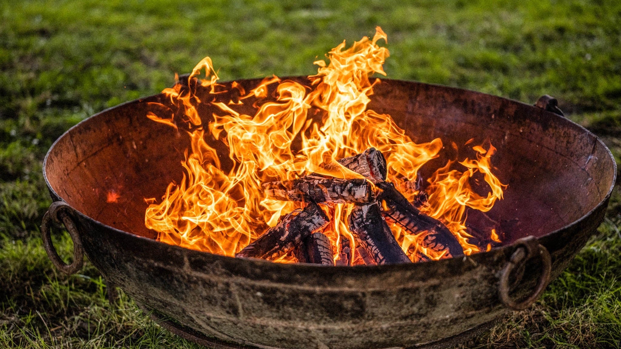 Kadai Original fire pit with flames burning on a grassy background