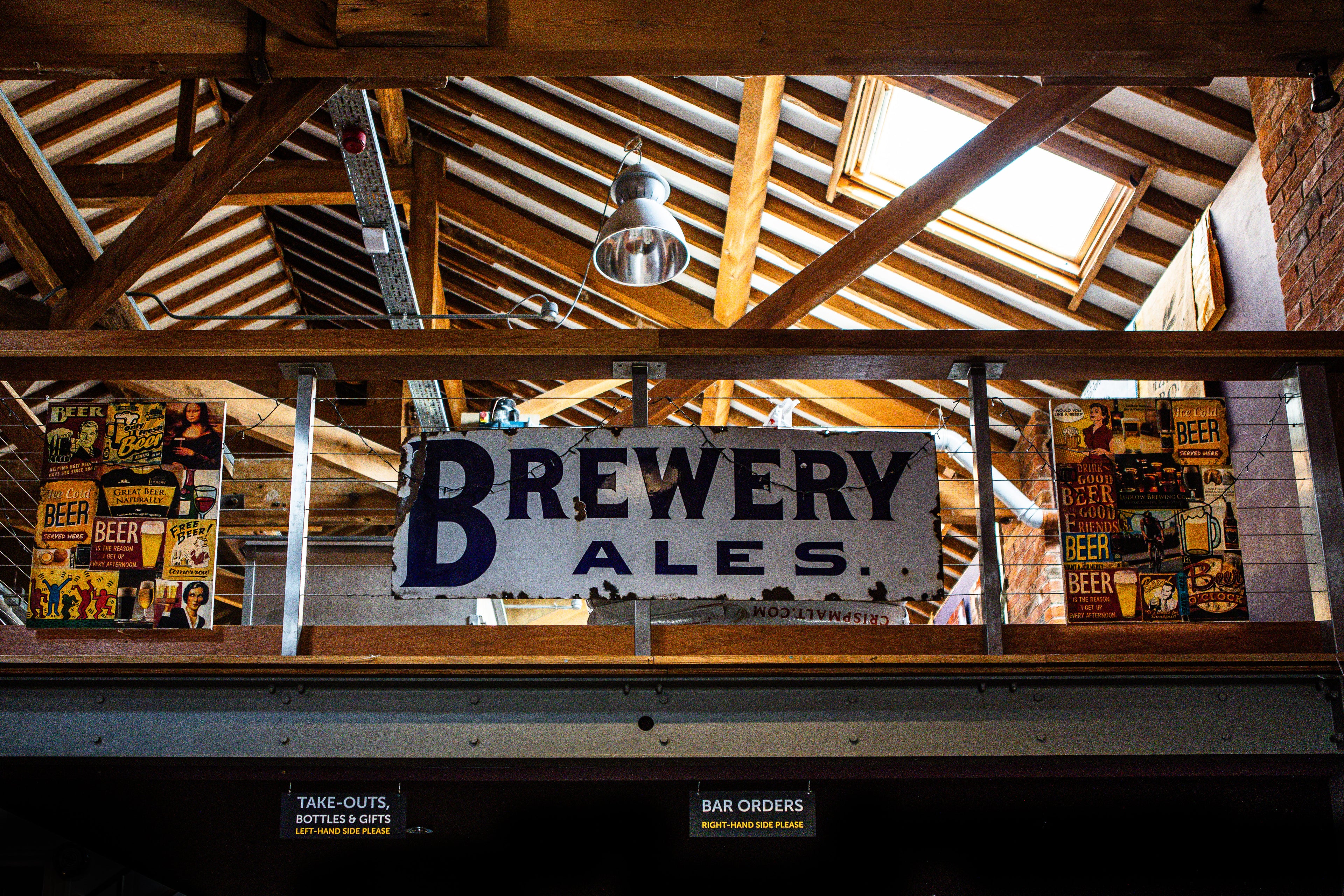 Brewery Ales sign hanging from a wooden ceiling with exposed beams