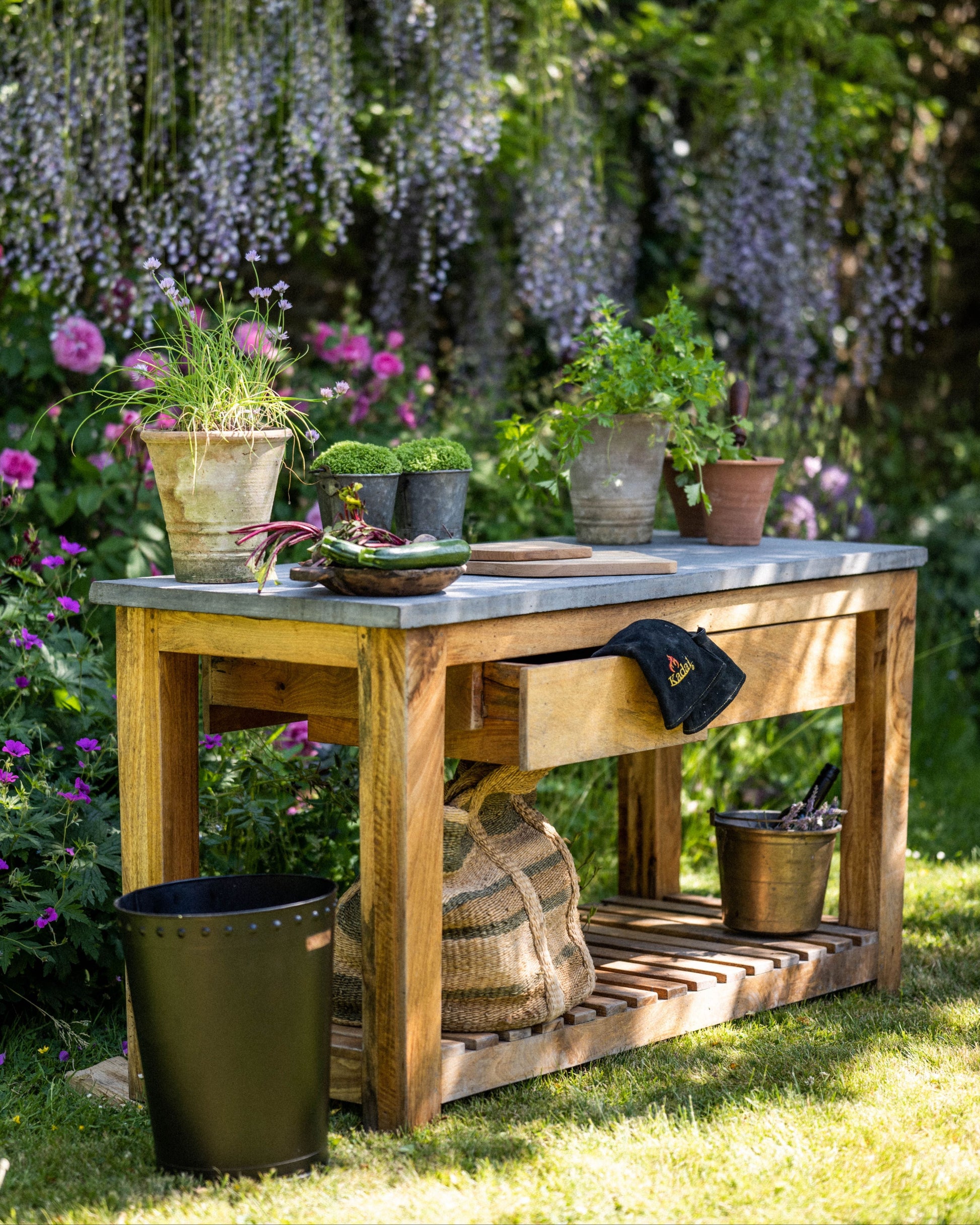 Wooden garden kitchen table with plants and tools in a lush garden setting