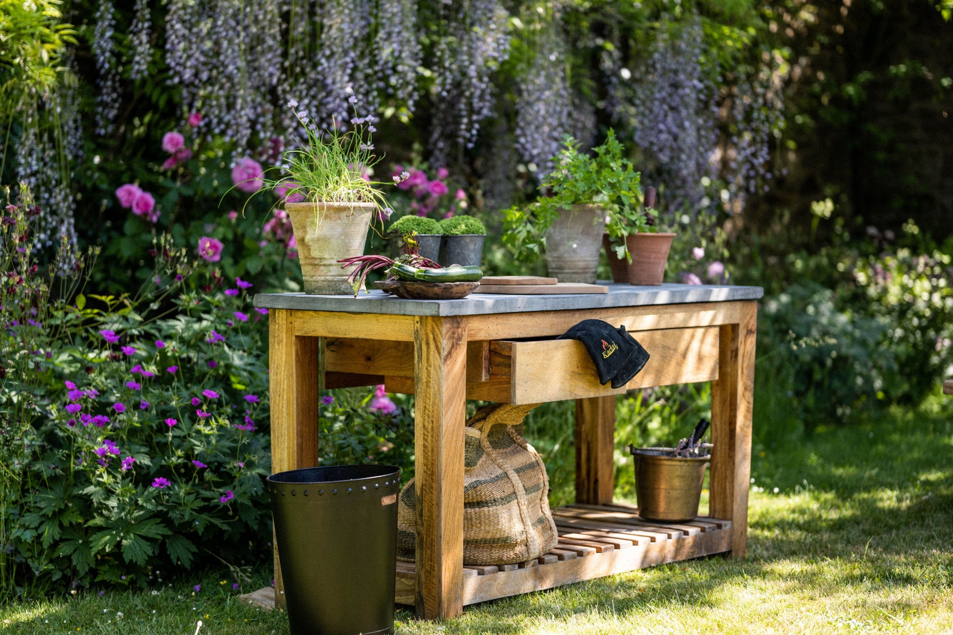 Wooden garden workbench with potted plants in a lush garden setting