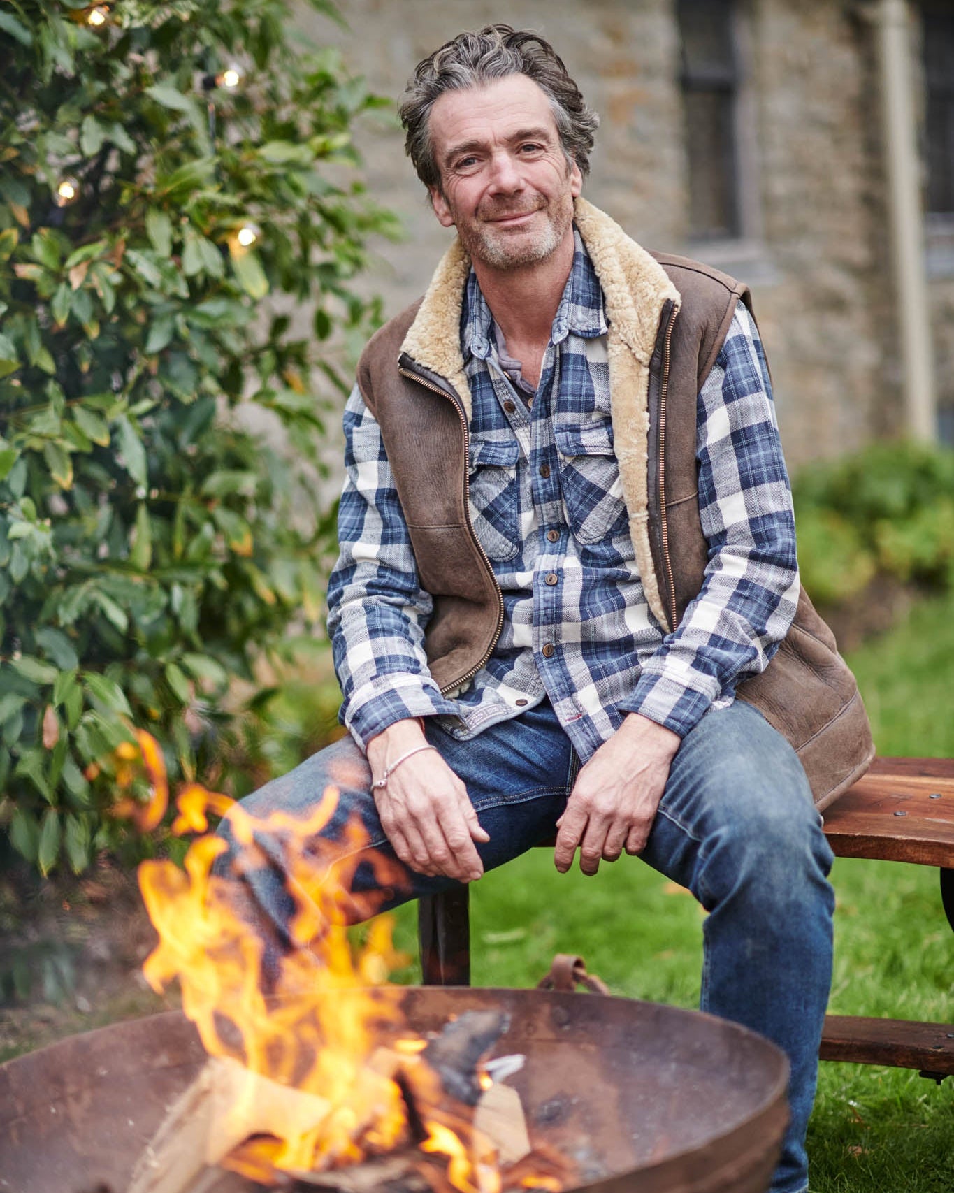 Man sitting by a kadai fire pit in a garden setting