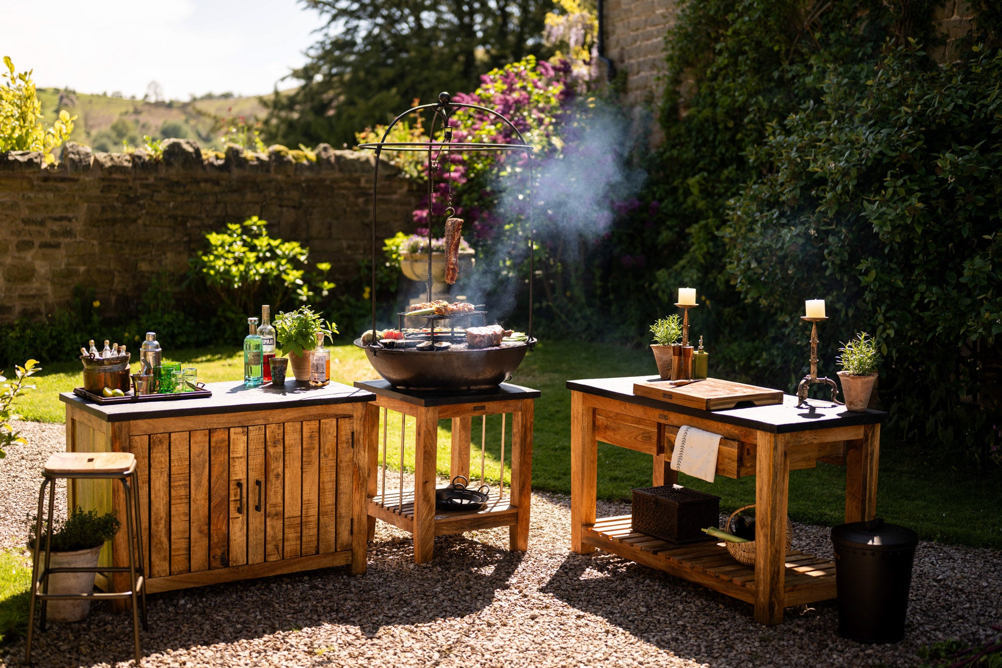 Rustic Kadai garden furniture and outdoor kitchen setup featuring handcrafted wooden preparation tables, live-fire cooking and timeless entertaining in the garden outdoors