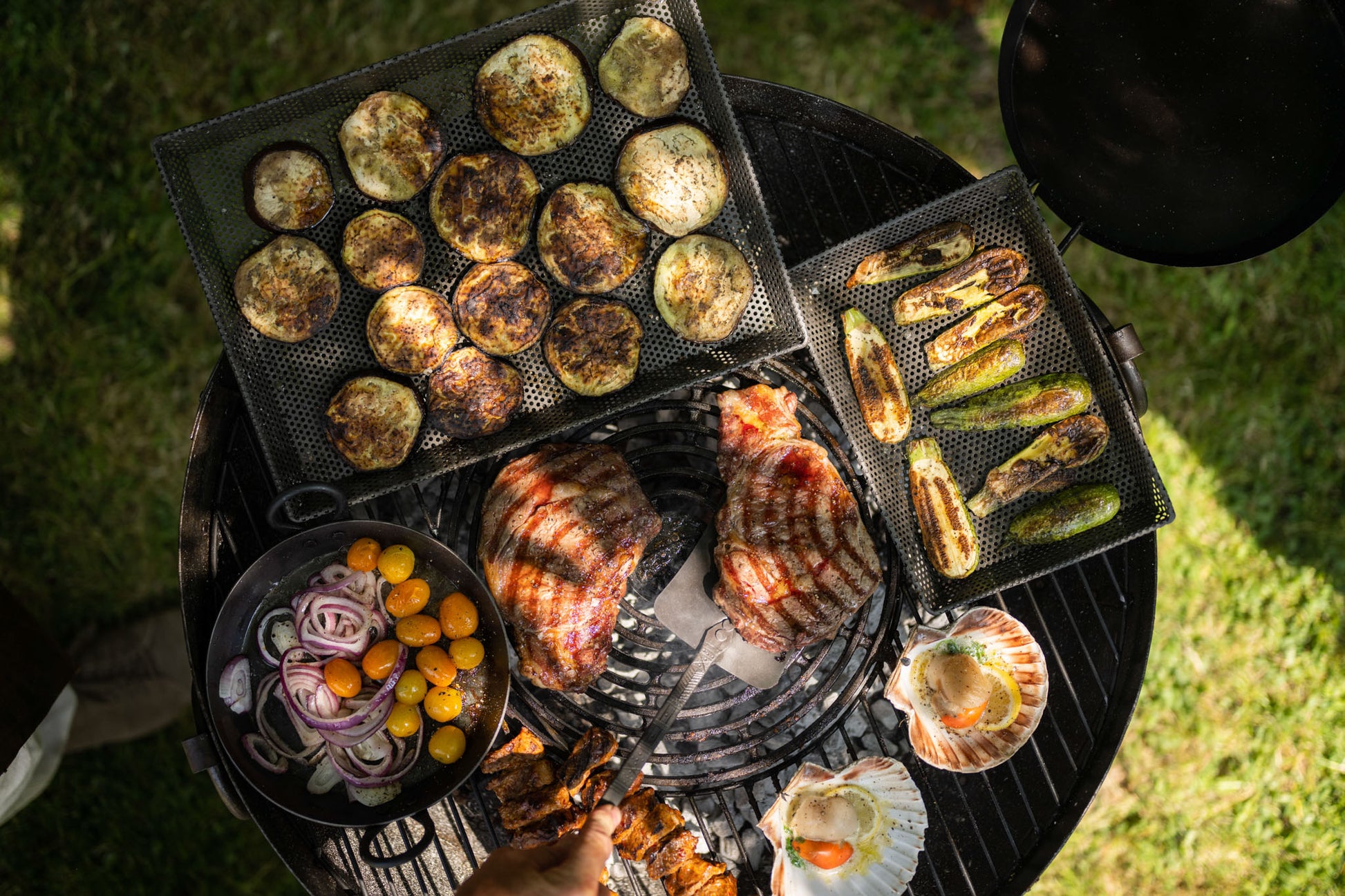 Grilled vegetables and meats on a kadai barbecue grill with a focus on the food.