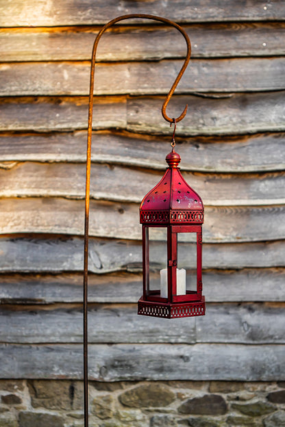 Red lantern with a candle inside hanging against a wooden wall.