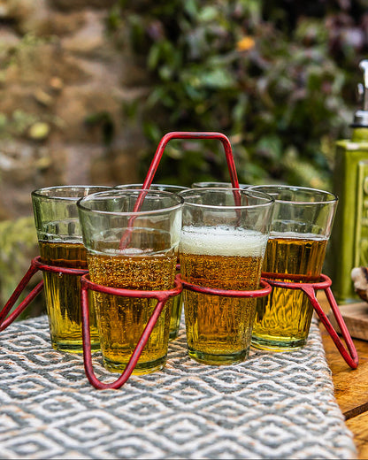 Kadai chai glass set with red metal stand holding six filled glasses on rustic table