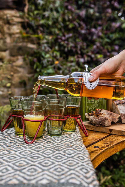 Set of chai glasses in red metal holder as drink is poured into glasses on outdoor table