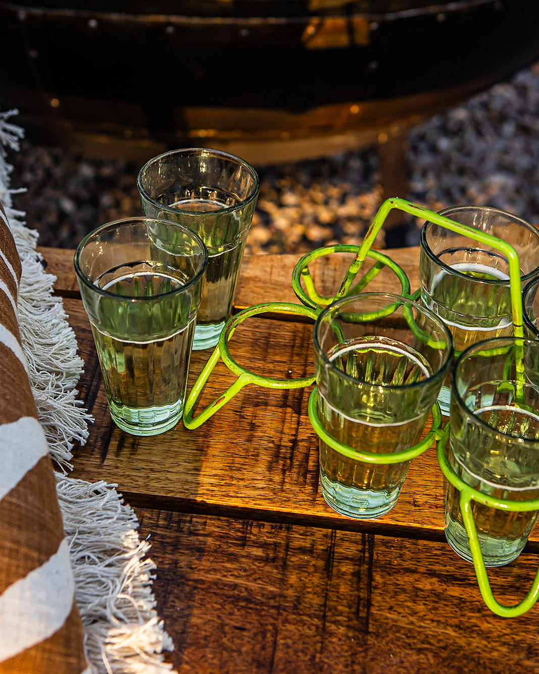 Wooden garden bench with drinks on a table beside it, outdoors.